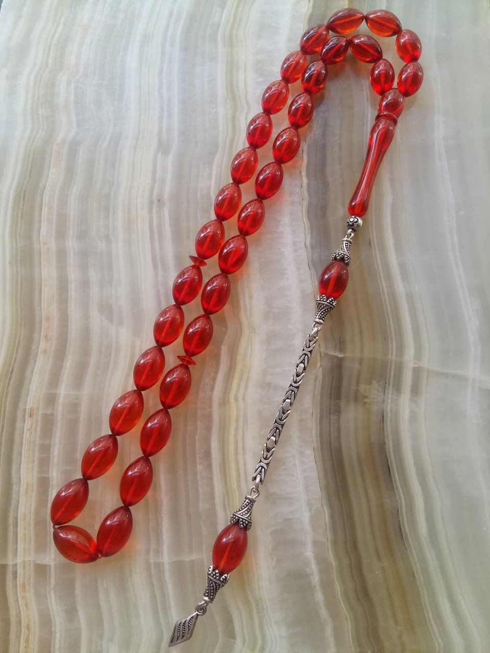 Özel İşçilikli Atölye Yapımı 925 Ayar Gümüş Püsküllü Ateş Kehribar Tesbih.Ürün Piyasanın en iyi Hammaddesinden Yapılmış Olup Canlı Rengiyle, Yumuşak Dokusu ve Kusursuz İşçiligiyle Tesbih Severlerin Beğenisine Sunulmuştur.