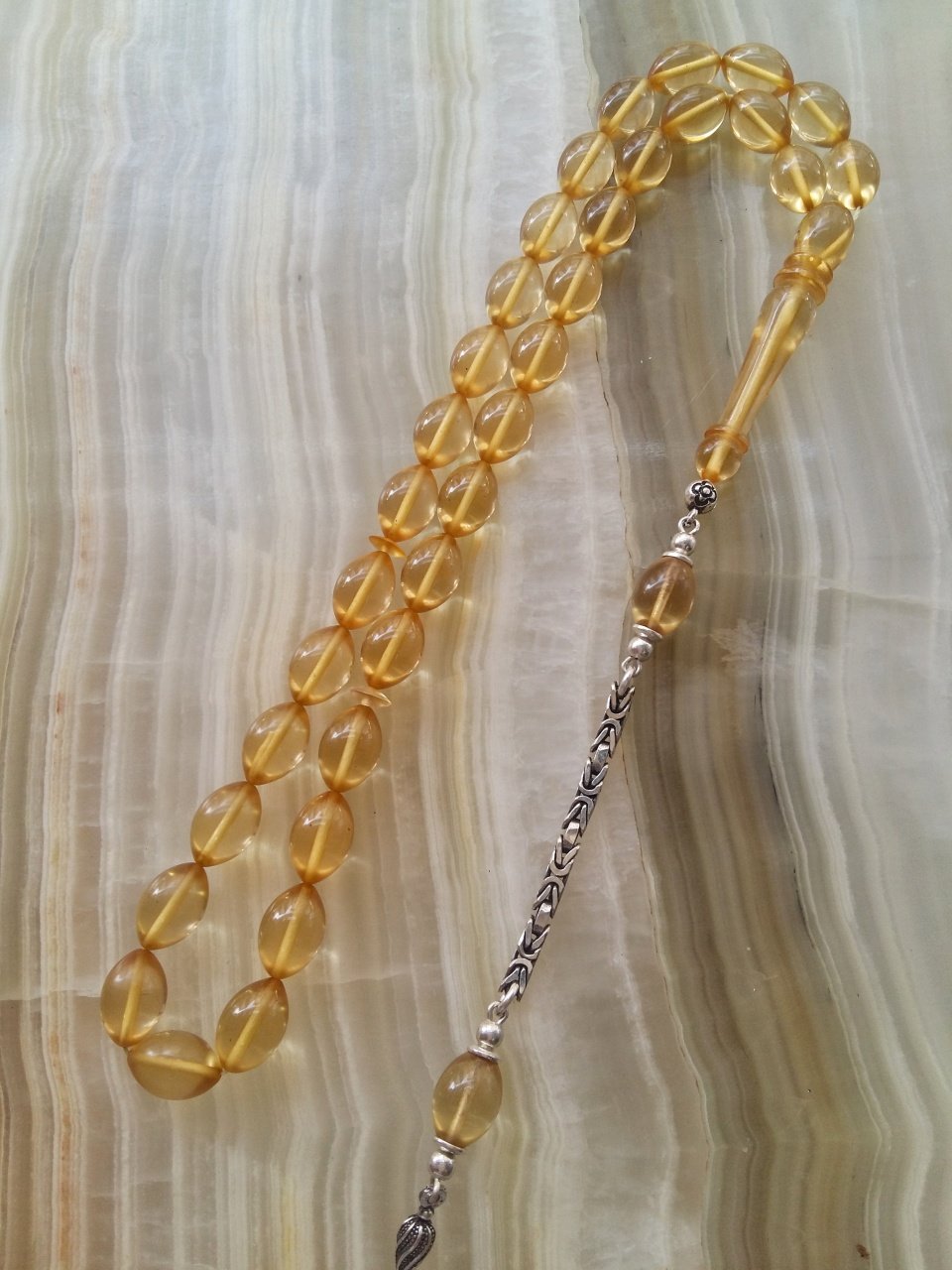 Özel İşçilikli Atölye Yapımı 925 Ayar Gümüş Püsküllü Ateş Kehribar Tesbih.Ürün Piyasanın en iyi Hammaddesinden Yapılmış Olup Canlı Rengiyle, Yumuşak Dokusu ve Kusursuz İşçiligiyle Tesbih Severlerin Beğenisine Sunulmuştur.