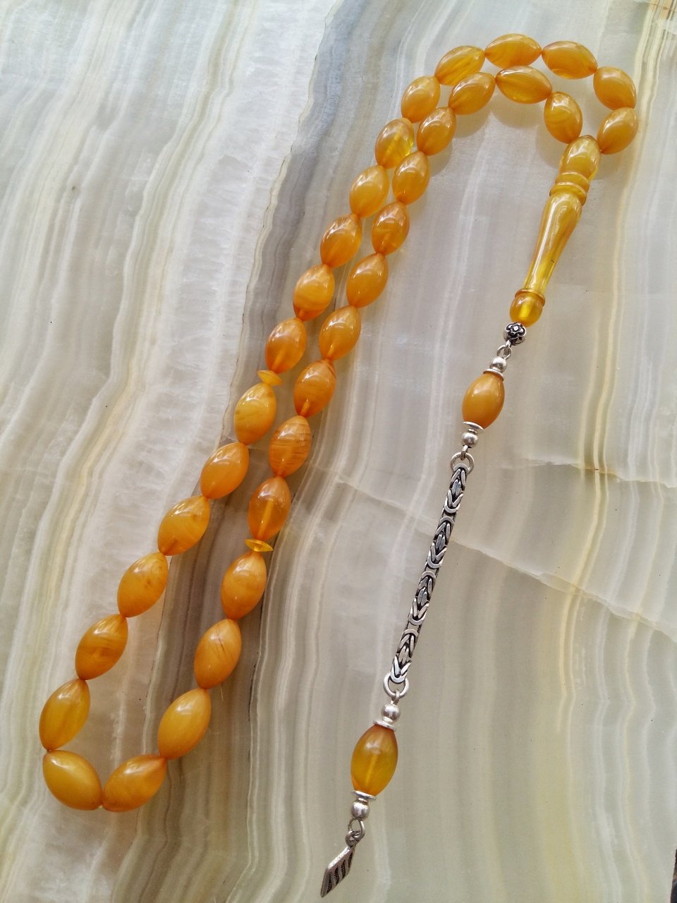 Özel İşçilikli Atölye Yapımı 925 Ayar Gümüş Püsküllü Sıkma Kehribar Tesbih.Ürün Piyasanın en iyi Hammaddesinden Yapılmış Olup Canlı Rengiyle, Yumuşak Dokusu ve Kusursuz İşçiligiyle Tesbih Severlerin Beğenisine Sunulmuştur.