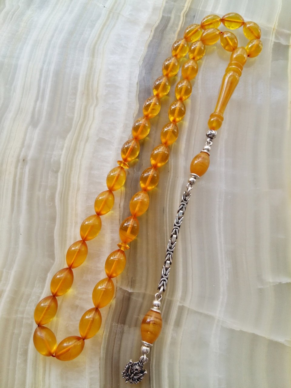 Özel İşçilikli Atölye Yapımı 925 Ayar Gümüş Püsküllü Sıkma Kehribar Tesbih.Ürün Piyasanın en iyi Hammaddesinden Yapılmış Olup Canlı Rengiyle, Yumuşak Dokusu ve Kusursuz İşçiligiyle Tesbih Severlerin Beğenisine Sunulmuştur.